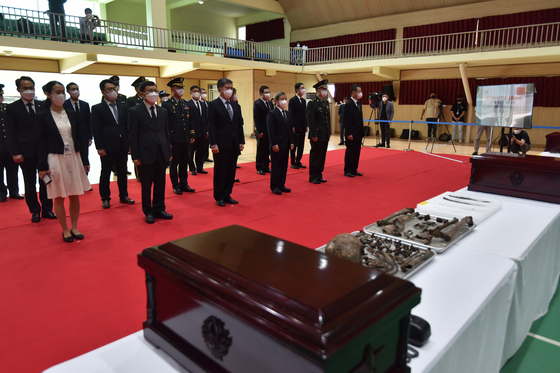 Military officials from South Korea and China pay their respects as the remains of 88 Chinese soldiers are placed in coffins in Incheon on Thursday. The Chinese soldiers were killed during the Korean War and their remains were recovered by a South Korean excavation unit. The coffins will be sent to China later. [DEFENSE MINISTRY]
