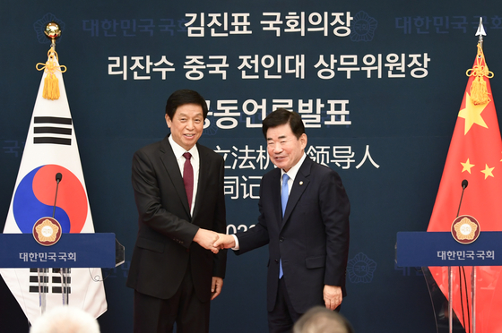 National Assembly Speaker Kim Jin-pyo, right, shakes hands with Li Zhanshu, chairman of China's Standing Committee of the National People's Congress, in a joint press conference in Seoul on Friday. [YONHAP] 