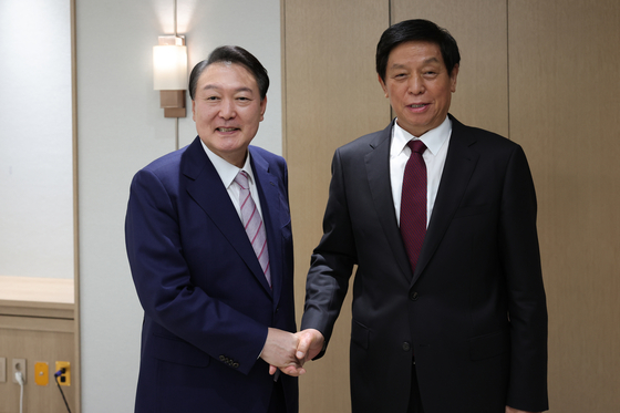 Korean President Yoon Suk-yeol, left, shakes hands with Li Zhanshu, chairman of China’s Standing Committee of the National People's Congress, in a meeting at the presidential office in Yongsan District, central Seoul, Friday. [PRESIDENTIAL OFFICE]