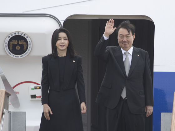 President Yoon Suk-yeol, right, accompanied by first lady Kim Keon-hee, waves at the Seoul Air Base in Seongnam, Gyeonggi, before heading on a weeklong trip Sunday morning to attend the state funeral of Queen Elizabeth II in London as a part of a seven-day, three-country trip that will also take them to the United States and Canada. [NEWS1]