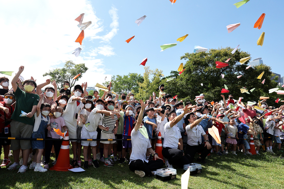 Children participating in the Han River Paper Airplane Festival fly paper planes at Yeouido Hangang Park in western Seoul on Sunday. The festival was resumed for the first time in three years due to the Covid-19 pandemic. [JANG JIN-YOUNG]