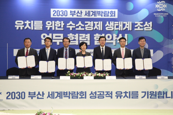 Environment Minister Han Hwa-jin, fourth from the left, and Busan Mayor Park Heong-joon, fifth from left, pose with representatives of SK E&S, Hyundai Motor, Busan Port Authority, Busan Technopark, and Busan Metrobus Company Association during a signing ceremony in Busan on Monday. [SK E&S]