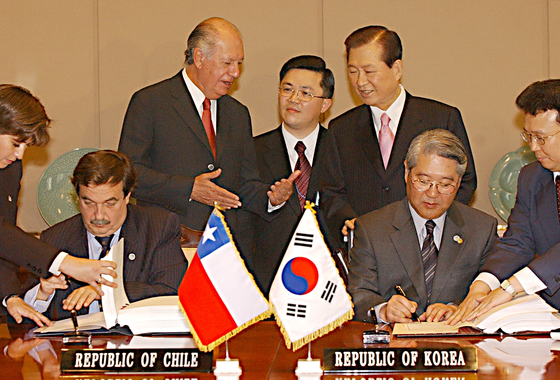Chile’s President Ricardo Lagos and Korea's President Kim Dae-jung oversee the signing of the free trade agreement between Chile and Korea in Seoul on Feb. 15, 2003. [JOONGANG PHOTO]