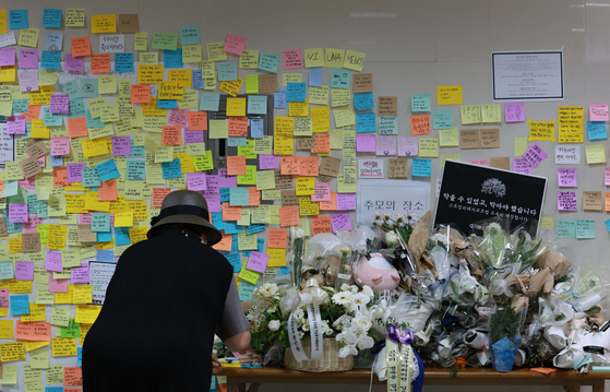 A woman writes a letter of condolence to a young subway worker outside a public restroom at Sindang Station in Jung District, central Seoul, on Sunday, four days after the worker was stabbed to death by her former colleague. [YONHAP]