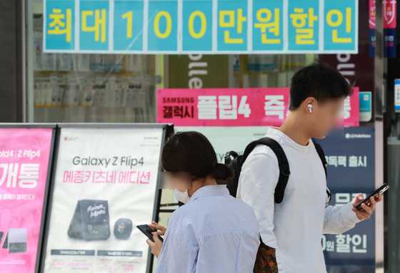 People pass by a mobile phone shop in Seodaemun District, southern Seoul on Tuesday. The number of people in their 20s with overdue phone bills reached 47,478 in July. These unpaid bills amounted to 6.4 billion won ($4.6 million), the highest among all age groups, according to data analyzed by independent lawmaker Yang Jung-suk's office ahead of a parliamentary audit. [YONHAP] 