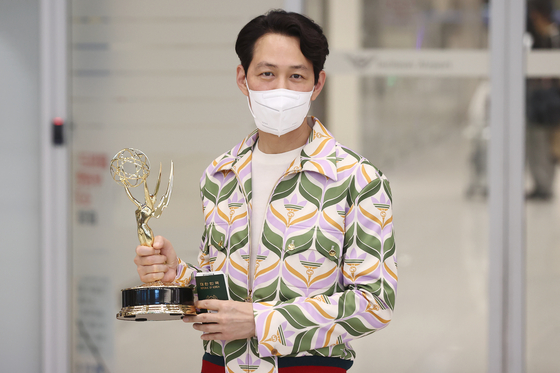 Actor Lee Jung-jae comes out of an arrival gate at Incheon International Airport on Sept. 18, holding an Emmy trophy in his hand. [YONHAP]