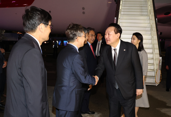 President Yoon Suk-yeol, right, accompanied by first lady Kim Keon-hee, shakes hands with officials after arriving at the John F. Kennedy International Airport in New York Monday. [YONHAP]