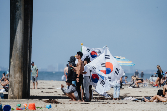 Members of the Korean national surfing team hold the Korean Taegukgi while watching the heats at the World Surfing Games in Huntington Beach, California. The Games ends a one-week run on Saturday.  [INTERNATIONAL SURFING ASSOCIATION]