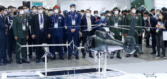 Foreign military officials observe a model of a Korean military helicopter exhibited at the Defense Expo Korea 2022, the biggest military weapon exhibition in the country, held at Kintex in Goyang, Gyeonggi, on Wednesday. The exhibition has been held every two years since 2014. This year, 350 companies are participating in the expo, an increase from 210 in 2020. This year, major military officers including defense ministers from 43 countries including Saudi Arabia, the United Arab Emirates, Slovakia and Romania are visiting. [YONHAP] 
