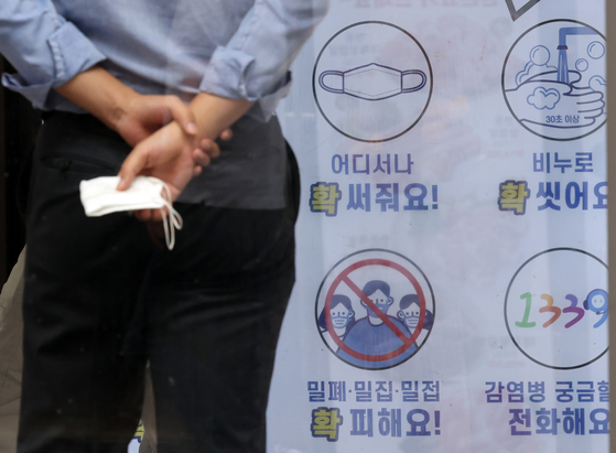 A person holds a face mask in Seoul on Thursday. The government is set to end the outdoor mask mandate as early as this week. [YONHAP]