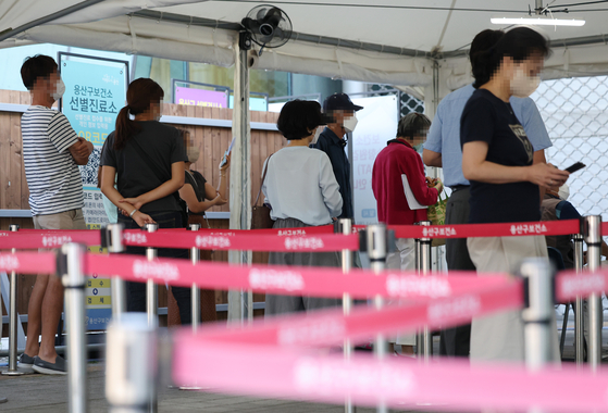 People line up to get tested for Covid-19 at a testing center in Yongsan District, central Seoul, on Friday. [YONHAP]