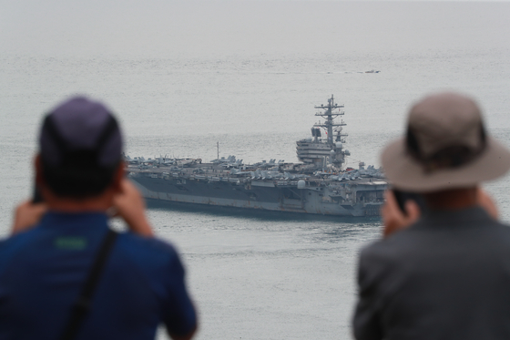 Onlookers in Busan take photographs of the aircraft carrier USS Ronald Reagan as it departs for joint exercises with the South Korean Navy on Monday morning. [YONHAP]