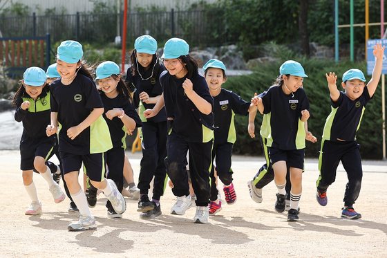 Not wearing masks, children frolic during a gym class in the playground of an elementary school in Seoul on Monday as masks are not required for outdoor group activities anymore. [YONHAP]