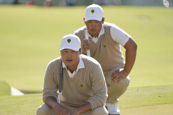 Lee Kyoung-hoon, left, and Kim Joo-hyung line up a putt on the 12th green during their foursomes match at the 2022 Presidents Cup at the Quail Hollow Club on Saturday. [AP/YONHAP]