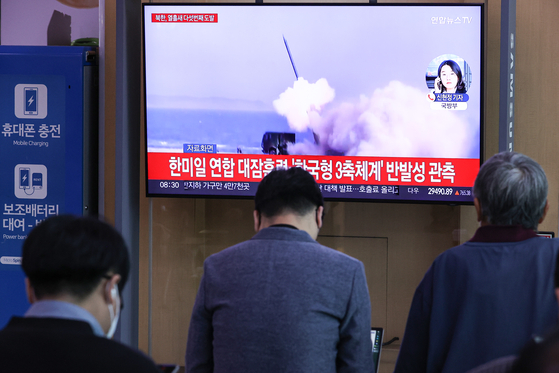 Passengers watch a news broadcast about North Korea's missile test on a television inside Seoul Station's main concourse on Tuesday morning.