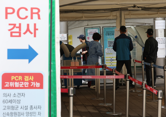 People wait outside a testing center in Yongsan District, central Seoul, on Wednesday. [YONHAP]