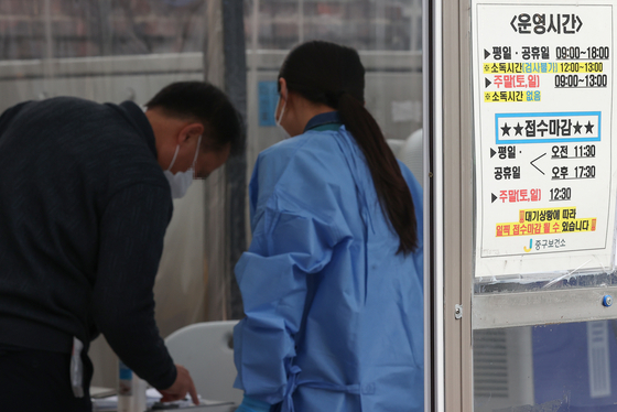A health worker explains testing guidelines for Covid-19 at a testing center in Jung District, central Seoul, on Thursday. [YONHAP]