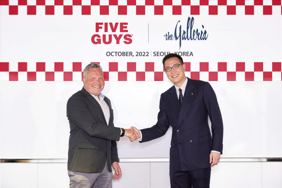 Kim Dong-seon, right, head of new business strategies of Hanwha Solutions' Galleria division, and William Peecher, vice president of Five Guys Enterprises International, pose for a photo after signing a licensing agreement on Wednesday. [GALLERIA DEPARTMENT STORE]