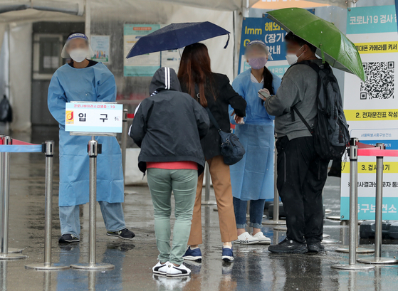 Health workers guide those who wish to get tested for Covid-19 at a testing center in Seoul Station Square in Jung District, central Seoul, on Sunday. [NEWS1]