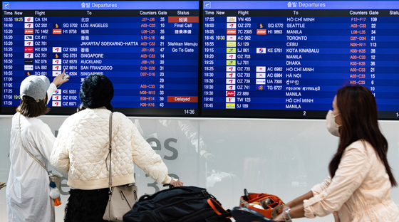 Passengers look at the departure board at Incheon International Airport on Monday, a day before the resumption of visa-free travel to Japan. [YONHAP]