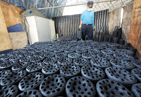 A worker moves coal briquettes at a briquette company in Hwaseong, Gyeonggi, on Tuesday afternoon as the weather becomes colder. [YONHAP]