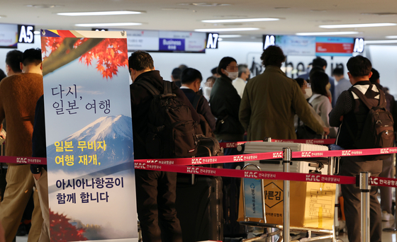 Passengers wait in a long line to check in at Gimpo International Airport for a flight to Tokyo's Haneda Airport on Tuesday. The sign in front reads "Back to traveling in Japan." [YONHAP]