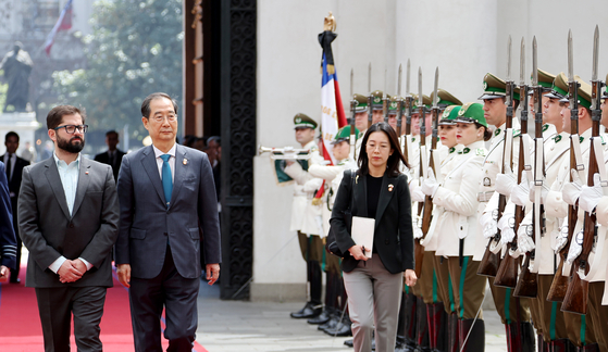 Korean Prime Minister Han Duck-soo, right, and Chilean President Gabriel Boric observe an honor guard before holding talks in Santiago, Chile, Wednesday. They agreed to elevate bilateral relations to a strategic partnership as the two nations mark the 60th anniversary of establishing diplomatic ties this year. [YONHAP]