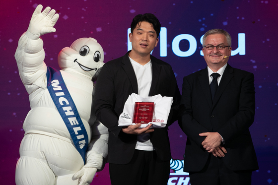 Chef Sung Ahn of Mosu, whose Korean name is Anh Sung-jae, center, poses on stage after his restaurant earned three Michelin stars at the Michelin Guide Seoul's Star Revelation ceremony on Thursday at Vista Walkerhill Seoul in eastern Seoul. [NEWS1]
