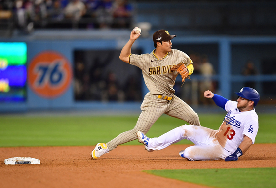 San Diego Padres shortstop Kim Ha-seong, center, turns a double play over Los Angeles Dodgers third baseman Max Muncy during the sixth inning of game two of the National League Division Series for the 2022 MLB Playoffs at Dodger Stadium in Los Angeles on Wednesday. The Padres beat the Dodgers 5-2, tying the series at 1-1. Kim picked up a hit in the third inning and later came around to score.  [USA TODAY/YONHAP]