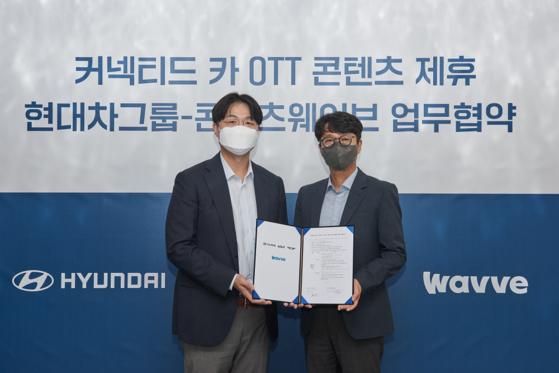 Paul Choo, left, executive vice president at Hyundai Motor's infotainment development center, and Wavve CEO Lee Tae-hyun pose for a photo after signing an agreement to develop a system that allows passengers to watch Wavve content in cars, on Monday in southern Seoul. [HYUNDAI MOTOR]