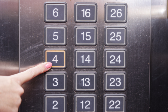 A passenger presses the button for the fourth floor in an elevator. [SHUTTERSTOCK]