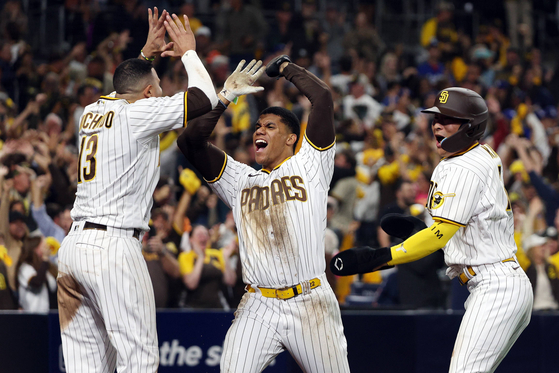 Kim Ha-seong of the San Diego Padres, right, celebrates with teammates Juan Soto, center, and Manny Machado after scoring two runs during the seventh inning to go up 5-3 against the Los Angeles Dodgers in game four of the National League Division Series at Petco Park in San Diego on Saturday. Kim batted in the tying run as the Padres went on to beat the Dodgers 5-3 to win the NLDS and advance to the National League Championship Series, where they will face the Philadelphia Phillies.  [AFP/YONHAP]