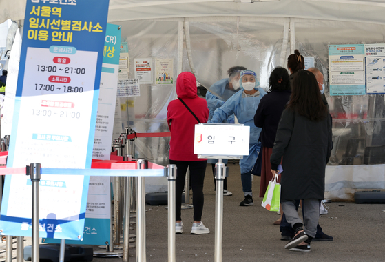 People stand in lne to gest tested for Covid-19 at a testing center in Jung-gu, central Seoul, on Monday. [YONHAP]