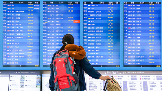 A traveler looks up at electronic boards showing flight information at Incheon International Airport Terminal 1 on September 14. [YONHAP]
