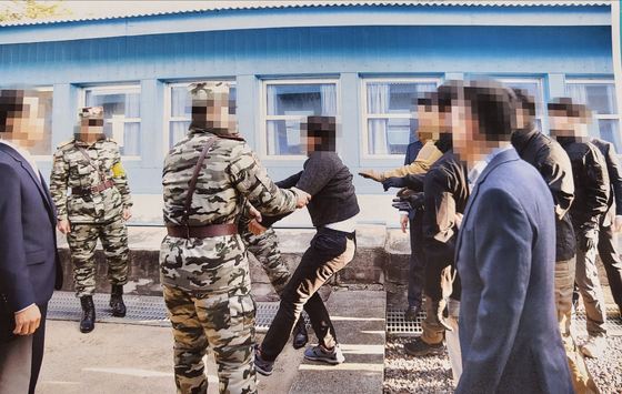 In a photograph released by the Unification Ministry in July, the first of the two North Korean fishermen to be repatriated via Panmunjom on Nov. 7, 2019 drags his feet as he is forced to return to the North. [UNIFICATION MINISTRY]
