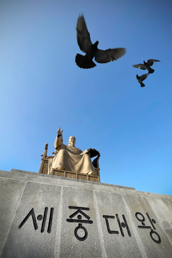 Birds fly above the statue of King Sejong the Great at Gwanghwamun Square. [ALLAND DHARMAWAN]