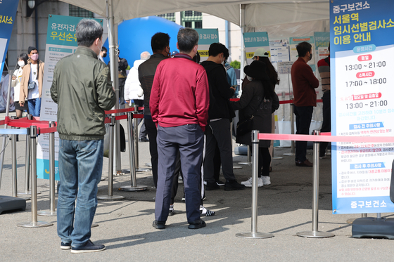 People stand in line to get tested for Covid-19 at a testing center near Seoul Station on Sunday. [YONHAP] 