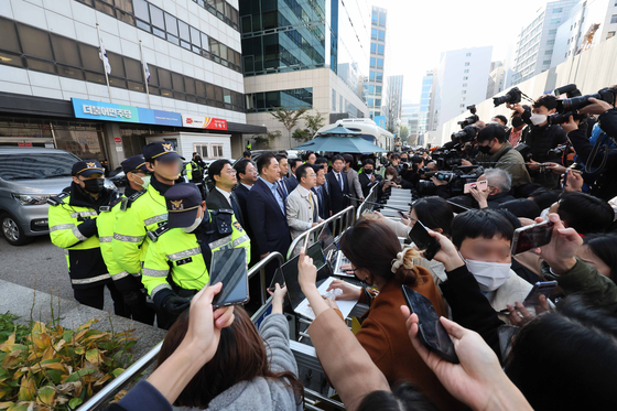 Police stand guard as Democratic Party (DP) lawmakers speak to reporters as prosecutors conduct a raid of a think tank in the party headquarters in Yeouido, western Seoul, Monday. [YONHAP]