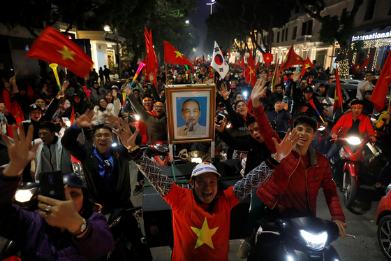 Vietnamese football fans celebrate with national flags and the image of late President Ho Chi Minh on the streets after the victory of Vietnam's U22 soccer team in South East Asia Games against Indonesia, in Hanoi, Vietnam, on Dec. 10, 2019. A korean flag is spotted among the flags of Vietnam held by football fans. [REUTERS/YONHAP]