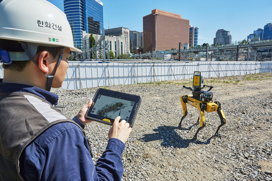 A Hanhwa E&C worker controls a robot dog at the company’s Seoul Station construction site on Sept. 27. [HANWHA ENGINEERING AND CONSTRUCTION]