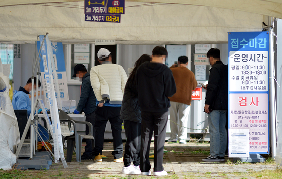 People stand in line to get tested for Covid-19 at a testing center in Daejeon on Tuesday. [JOONGANG ILBO]