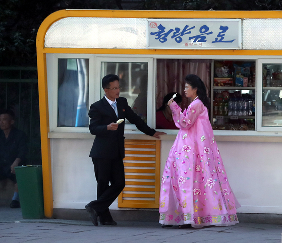 North Koreans enjoy ice cream on a street in Pyongyang in a press pool photo taken on Sept. 18, 2018. [YONHAP]