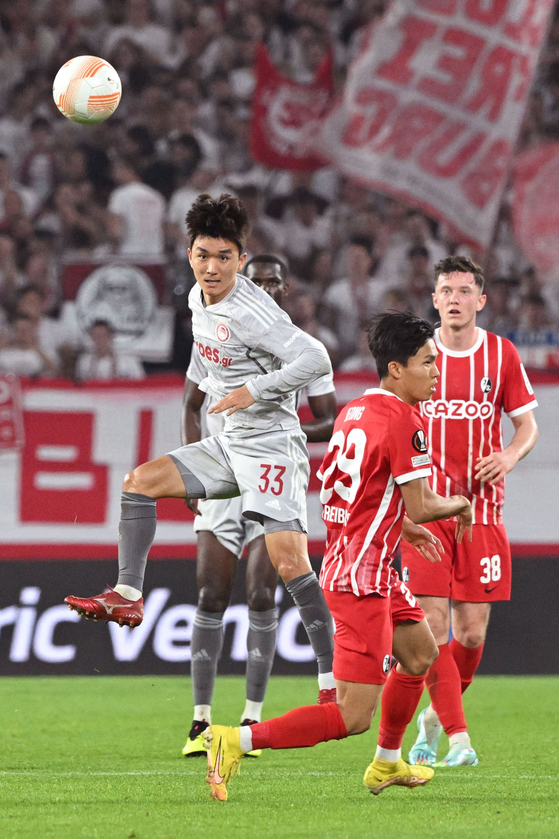 Olympiacos midfielder Hwang In-beom, center, kicks the ball passed Freiburg's Jeong Woo-yeong during a UEFA Europa League Group G match between SC Freiburg and Olympiacos in Freiburg, Germany on Thursday. [AFP/YONHAP]