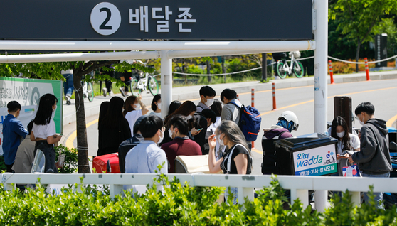 People stand around a delivery zone to pick up their food in Yeuouido Hangang Park on May 2, 2021. [NEWS1]