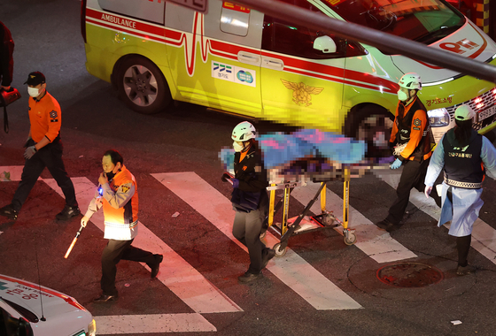 First responders move bodies from Itaewon, Seoul, Sunday. [YONHAP]