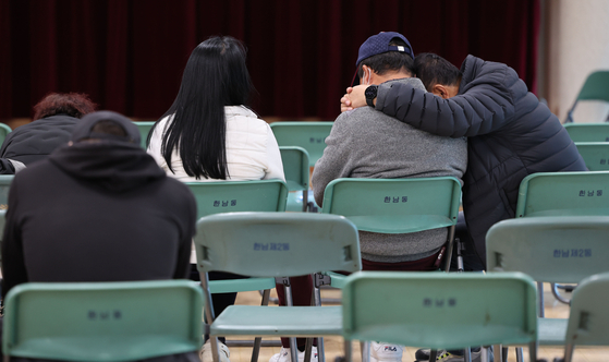 People wait for news about persons missing after a crowd crush in Itaewon. They comfort one another as they await updates at the Hannam-dong Community Service Center in Yongsan District, central Seoul, on Sunday. [YONHAP]
