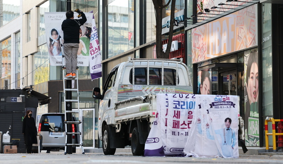 A worker takes down banners promoting the Korea Sale Festa at Myeongdong, central Seoul, in respect of those affected by the accident at Itaewon. [YONHAP] 