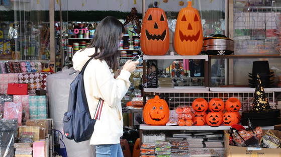 A passerby walks past a store with Halloween decorations at a traditional market in Seoul on Monday. Many businesses have discarded their Halloween-themed ads after a crowd crush claimed at least 154 lives. [YONHAP]