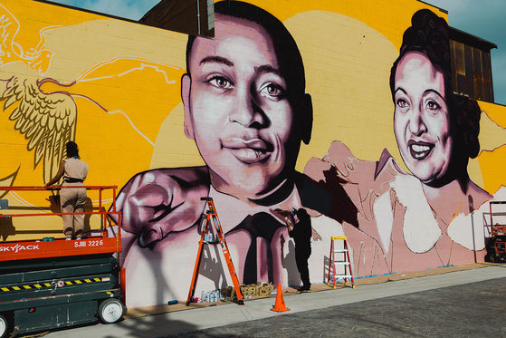 Artist Brandan “BMike” Odums, right, works with artist Whitney Alix on a mural depicting Emmett Till and his mother Mamie Till-Mobley in Los Angeles on Oct. 22. The mural is part of a collection called “Impact of Images” and was commissioned by Lead With Love, in collaboration with the studio and production company behind the film “Till.” [AP/YONHAP]