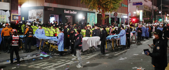 First responders and firefighters early Sunday morning wait in a line to transfer the dead from a surge that killed at least 153 people in Itaewon. [NEWS1]